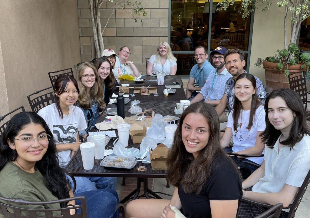Group of students and researchers sitting at a table outside